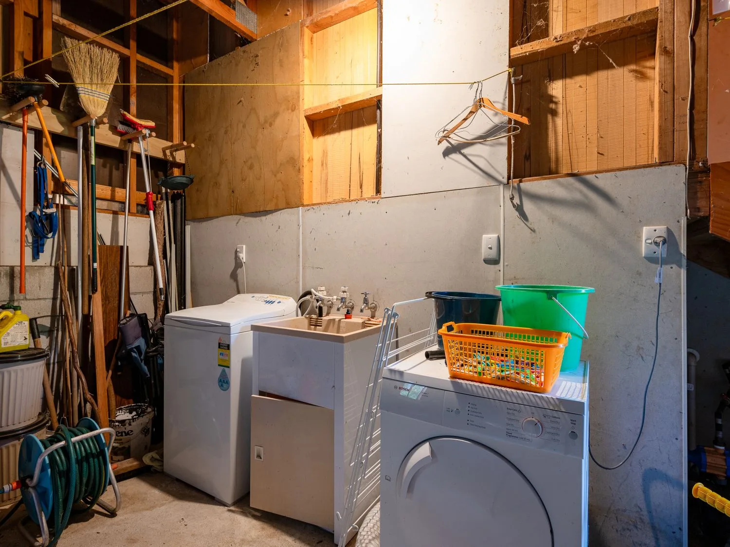 A laundry room with a washing machine dryer utility sink cleaning tools and buckets at Lake View Lodge Taupo Holiday Home in Pukawa Bay