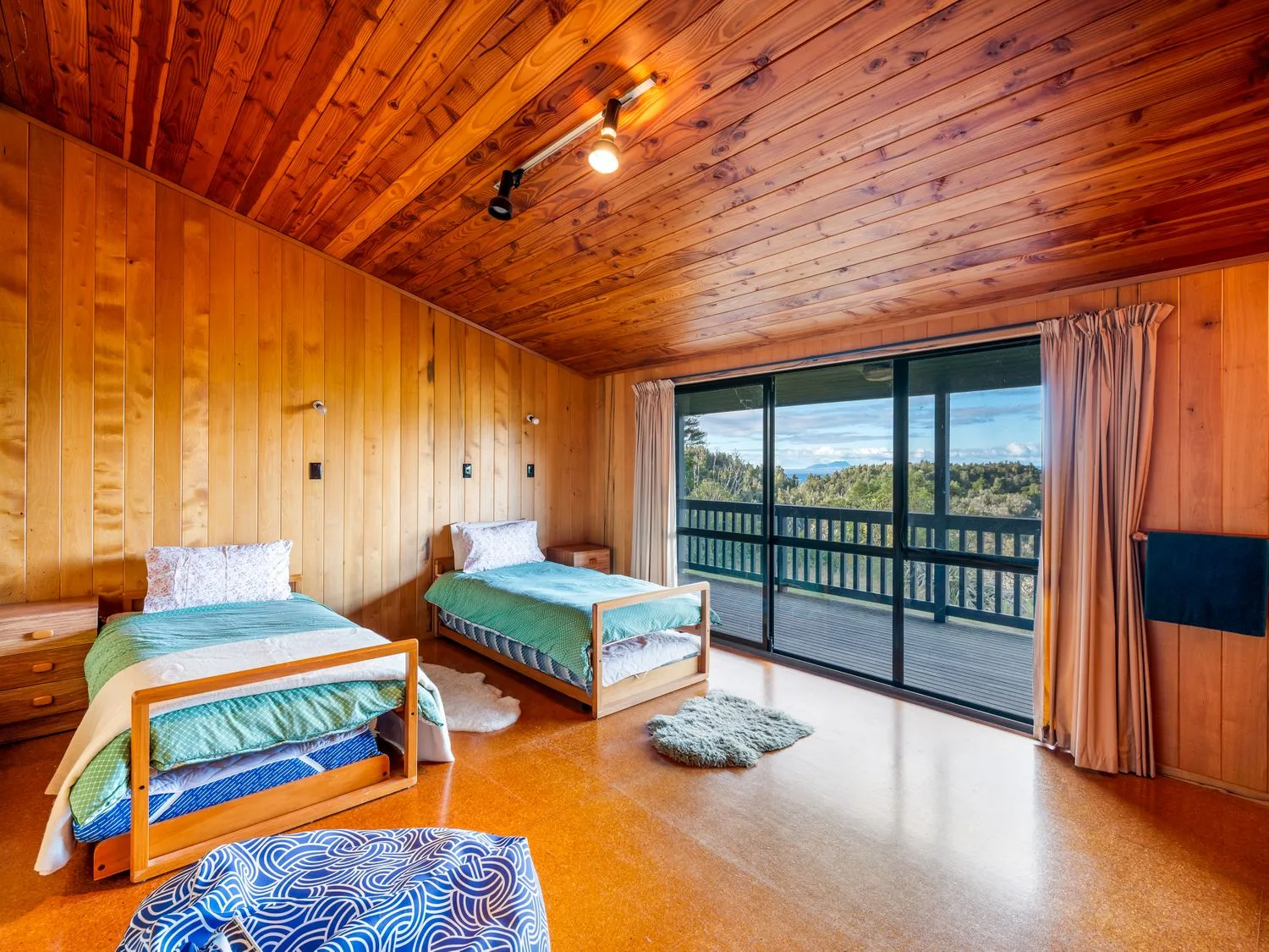A bedroom with two single beds beside sliding glass doors opening to a balcony at Lake View Lodge - Taupo Holiday Home in Pukawa Bay