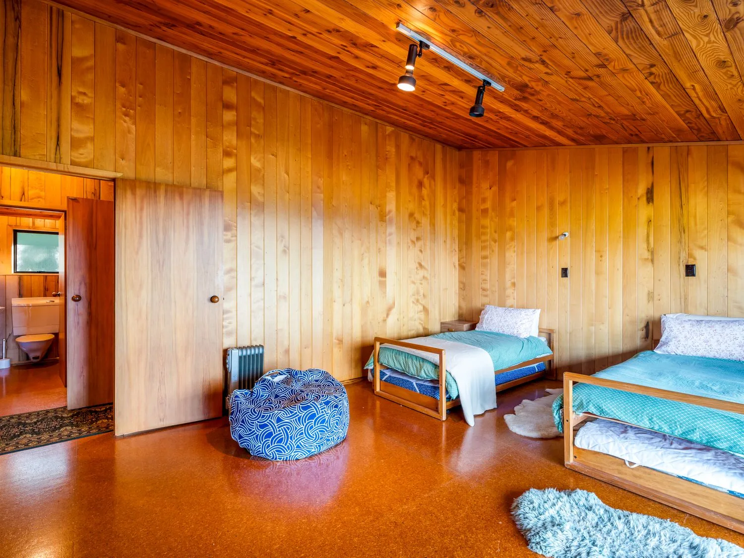 A bedroom with two single beds a bean bag and a radiator at Lake View Lodge - Taupo Holiday Home in Pukawa Bay
