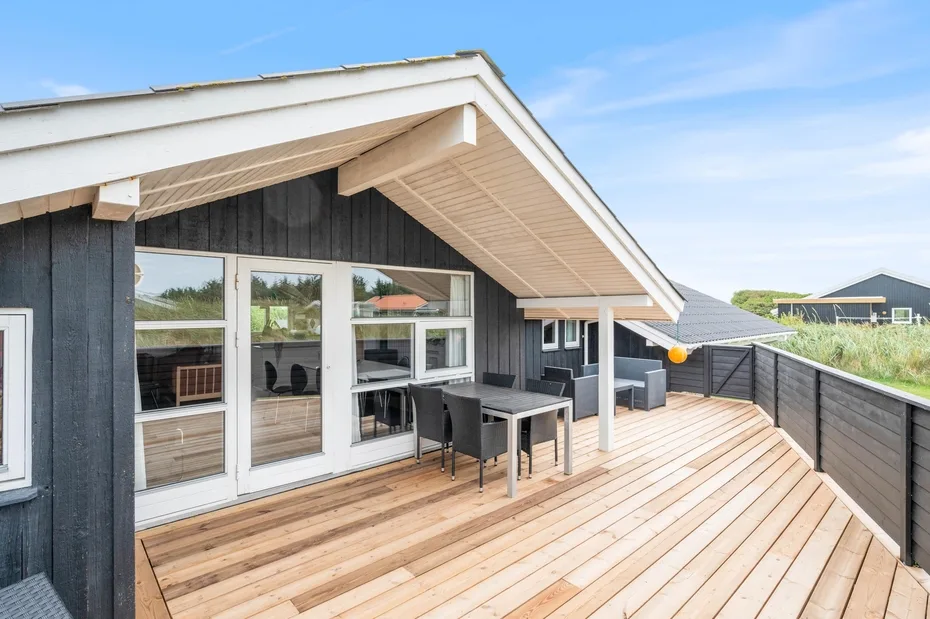 Una terraza exterior cubierta con asientos y amplias puertas de vidrio.