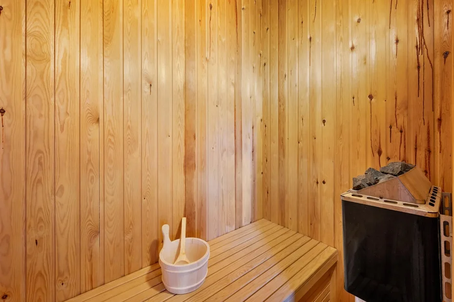 Una sauna con paredes de madera, un calentador y un cubo.