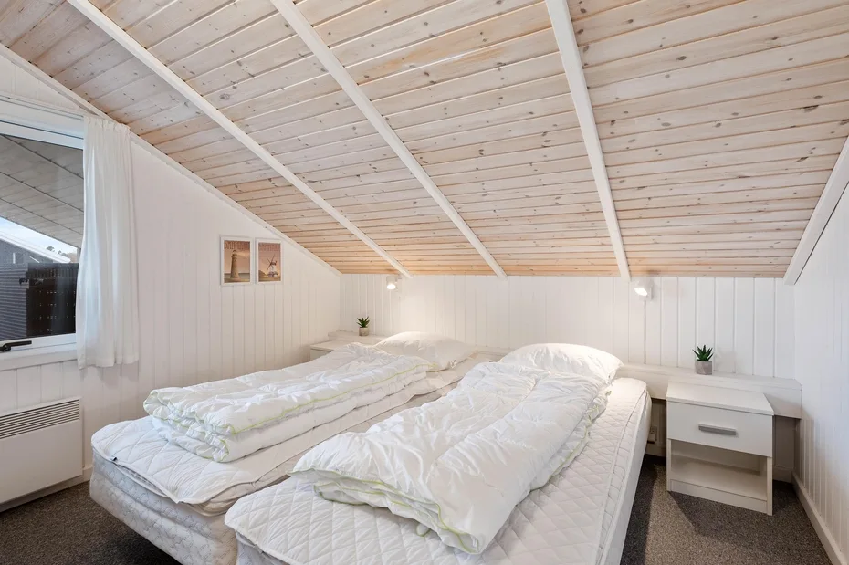 Un dormitorio con dos camas bajo un techo inclinado revestido de madera.