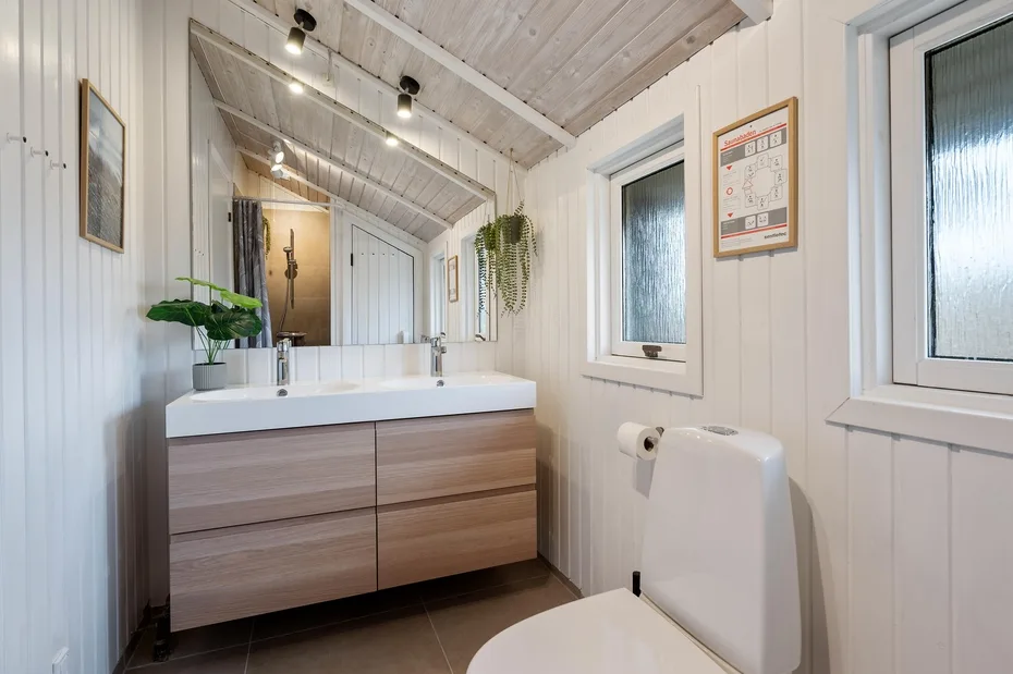 Un baño luminoso con un amplio tocador, espejo e inodoro.