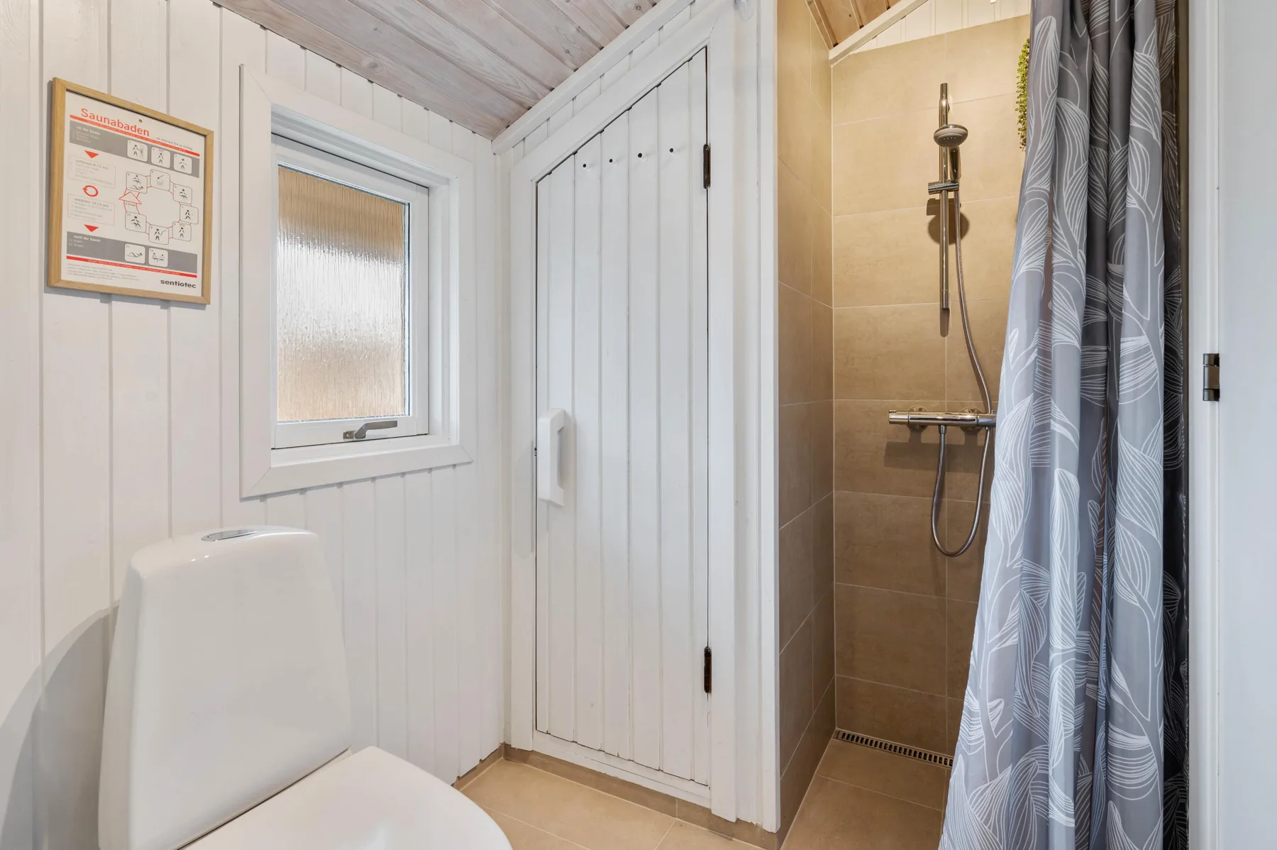 Un baño con un inodoro junto a una ducha.