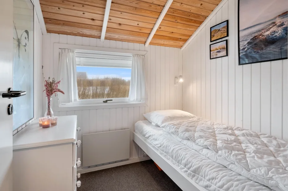 Un dormitorio con una cama bajo cuadros enmarcados y una ventana.