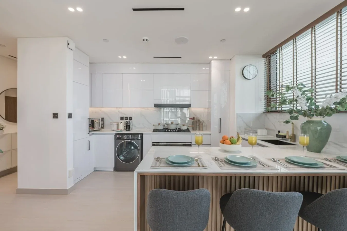 Una cocina moderna y luminosa con una isla de comedor preparada con platos y vasos.