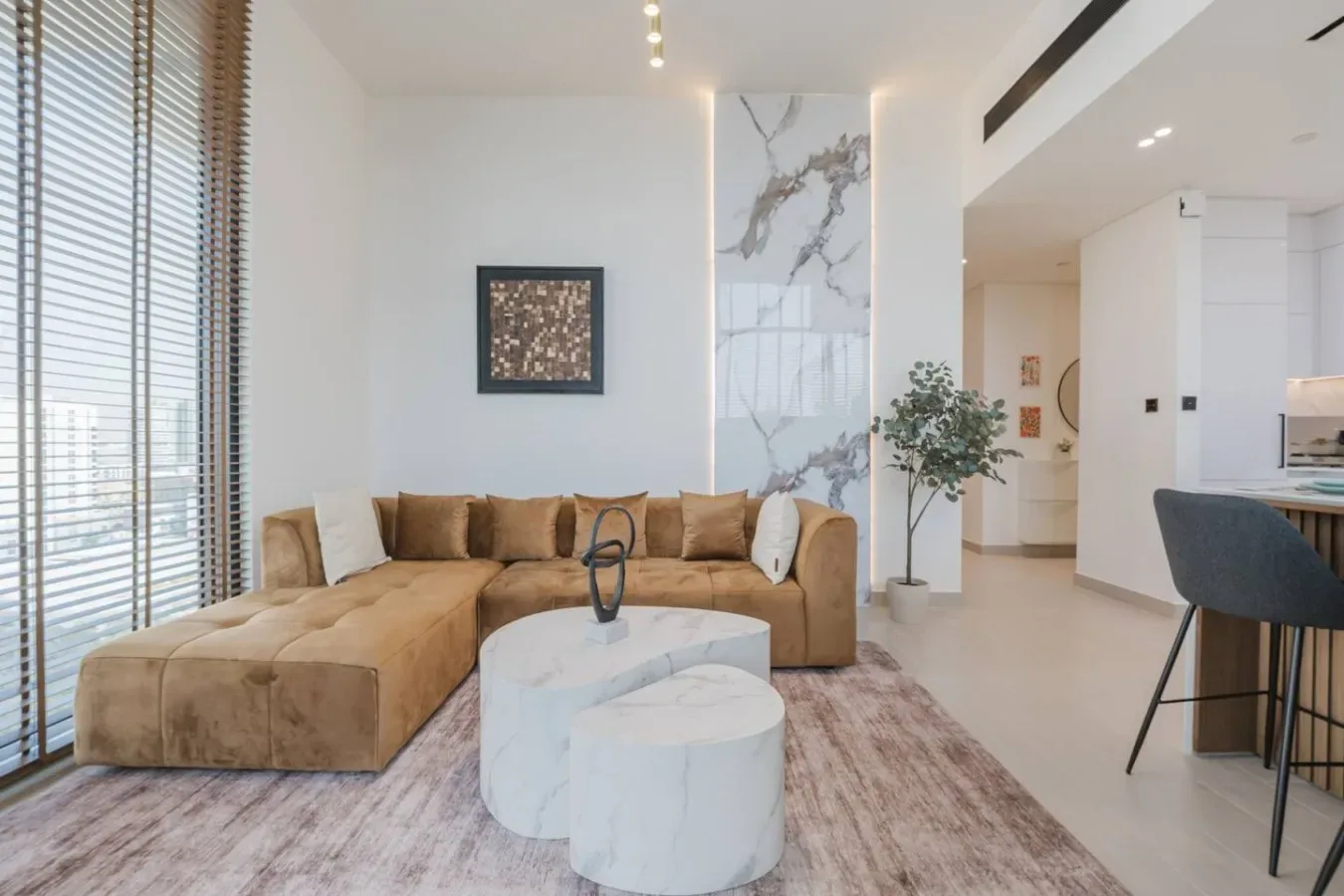 A bright living room with sectional seating, round tables, and tall windows.