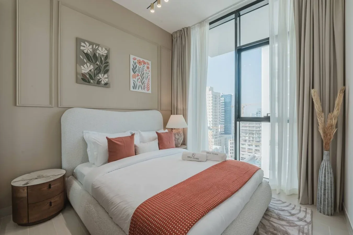 Dormitorio con una cama bien tendida junto a una ventana grande.