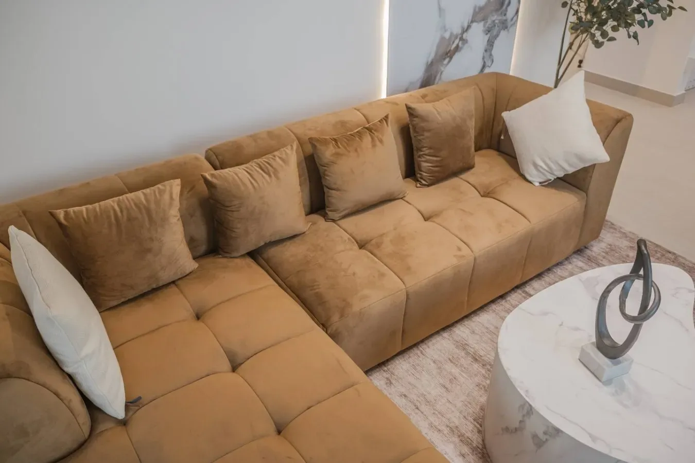 Una zona de estar con un sofá color canela y una mesa de centro redonda.