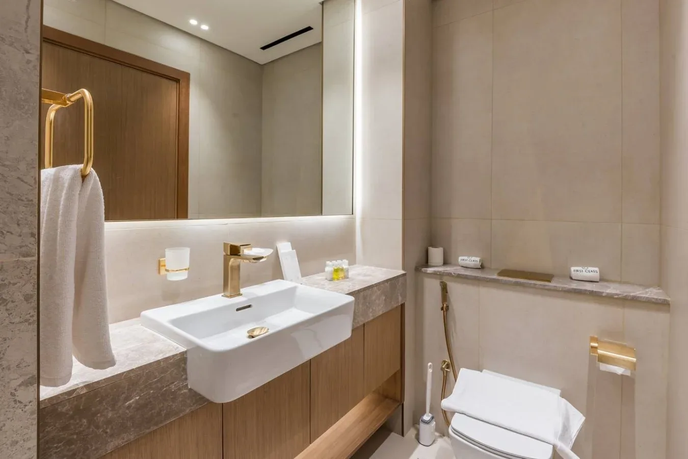 Un baño moderno con lavabo suspendido, espejo e inodoro.
