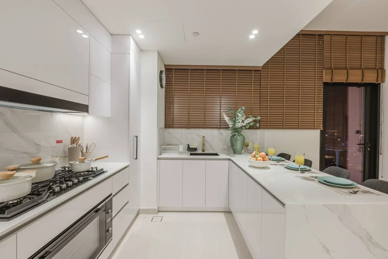 Una cocina moderna con encimeras blancas y persianas de madera.