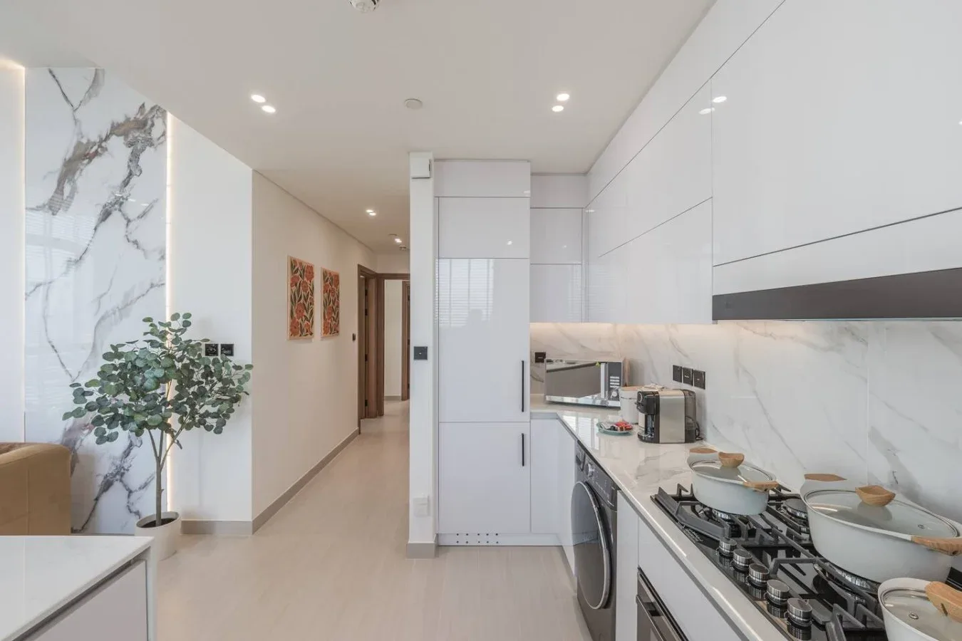 Una cocina moderna y luminosa, con gabinetes blancos y una larga encimera.