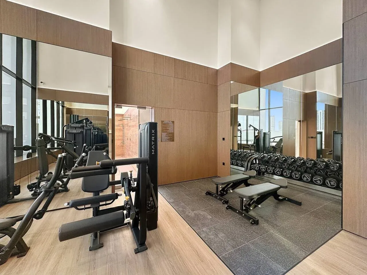 Una sala de fitness con máquinas de ejercicio, pesas y paredes espejadas.