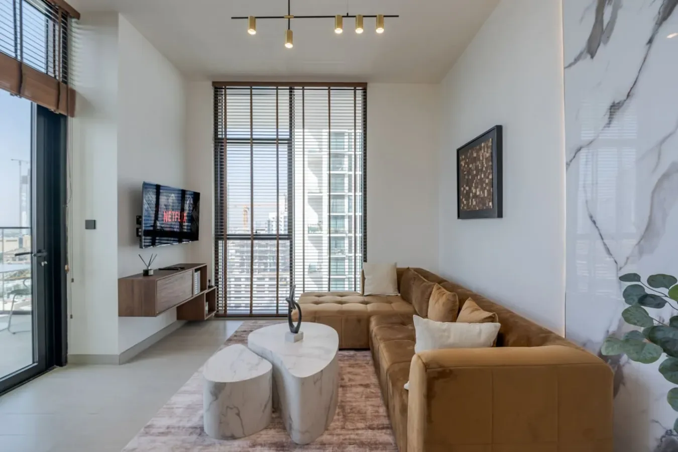 A bright living room with a brown sectional, coffee table, and large windows.