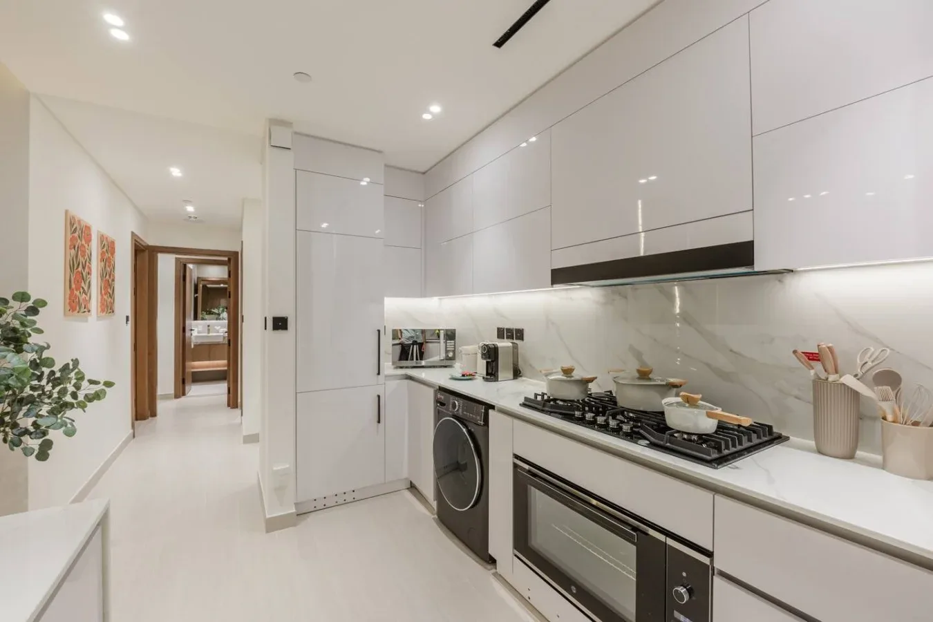 Una cocina moderna y luminosa con gabinetes blancos y una larga encimera.