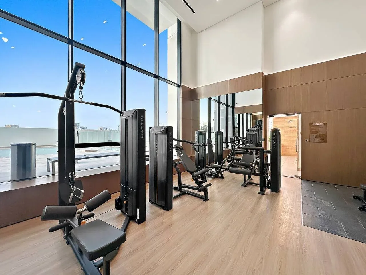 Un gimnasio con máquinas de ejercicio junto a ventanales.