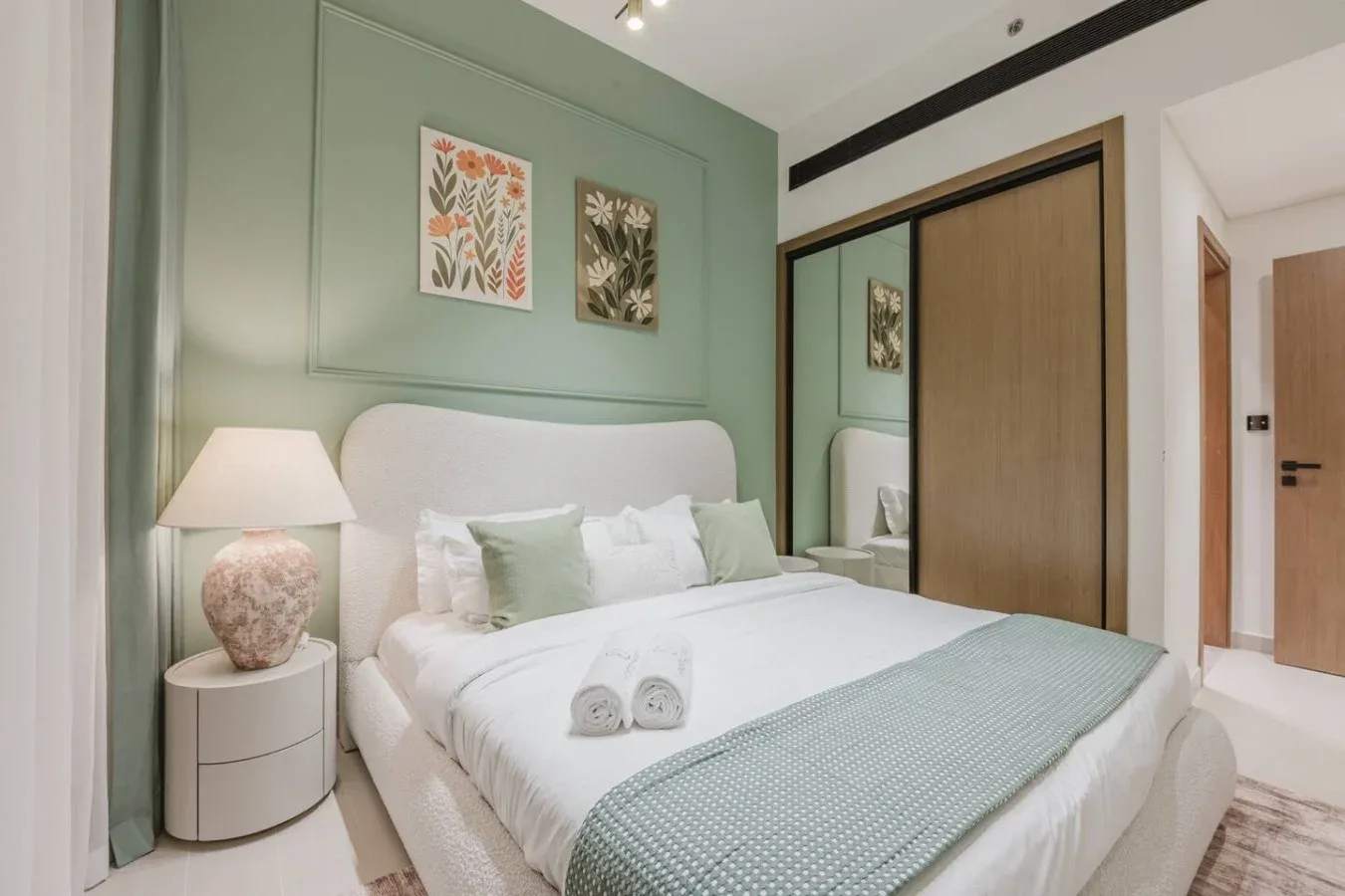 Un dormitorio con una cama bien tendida y detalles en tonos verde claro.