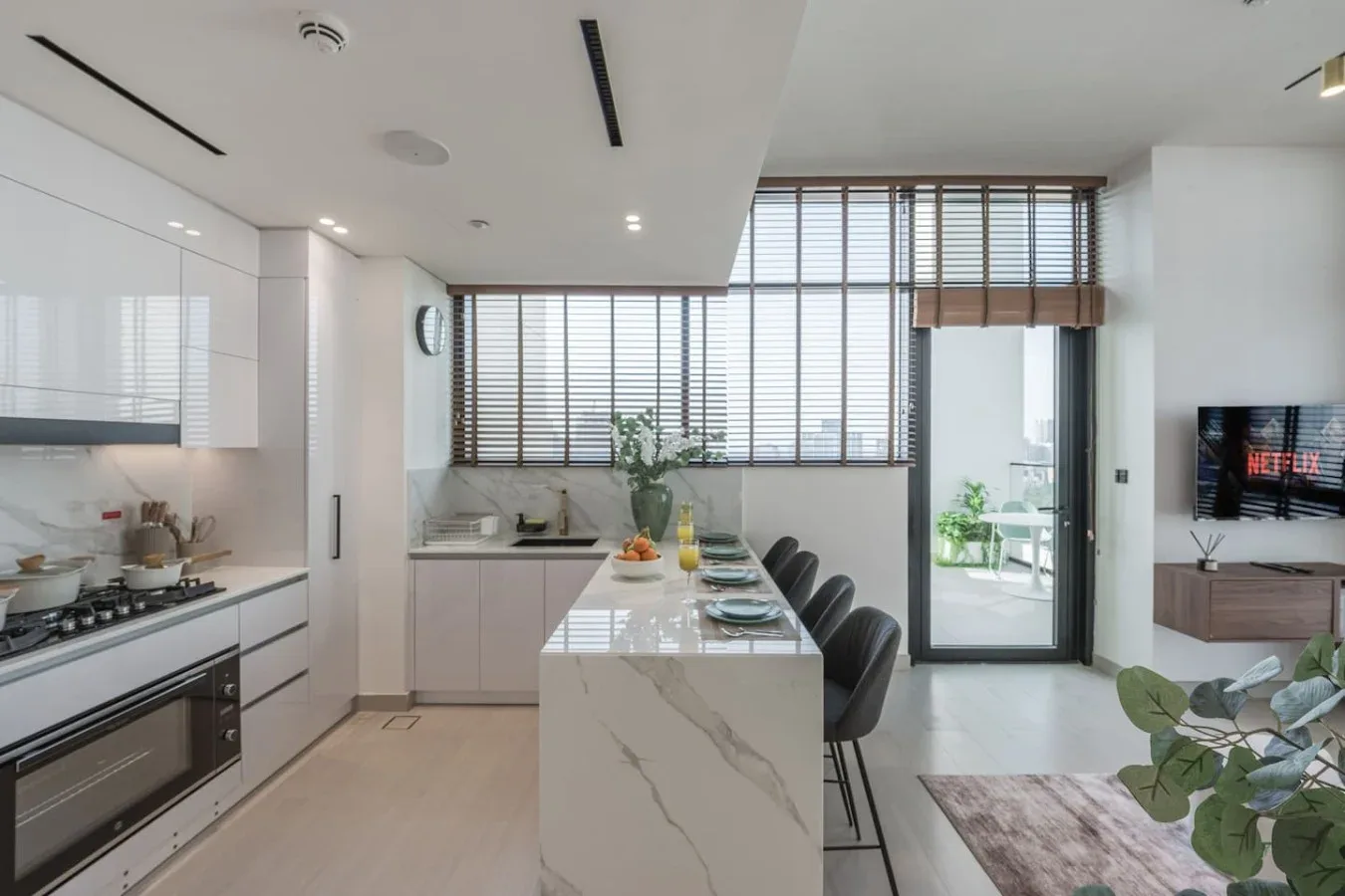 Una cocina y comedor modernos y luminosos, con una isla alargada y grandes ventanas.