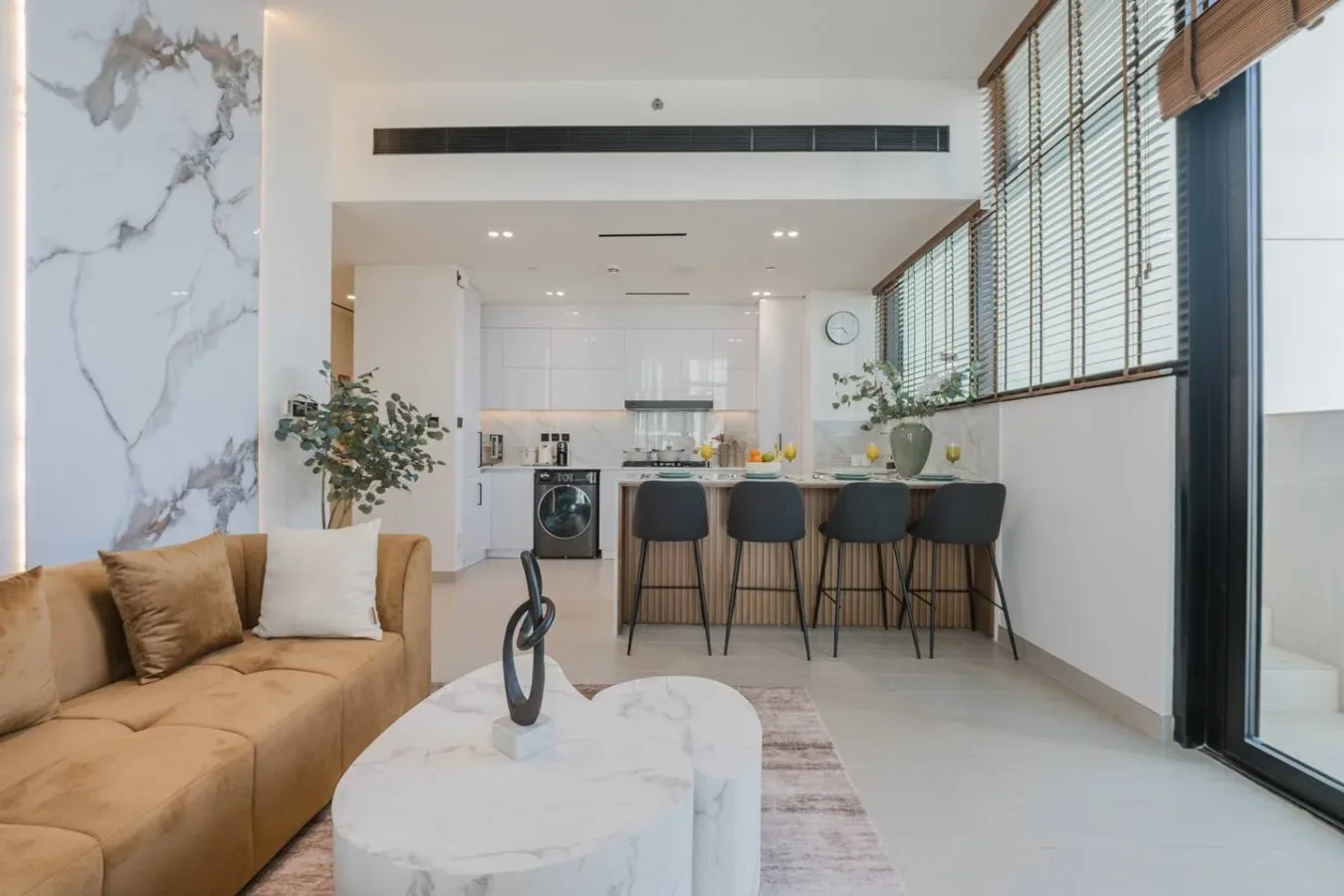 Una luminosa sala de estar y cocina de concepto abierto, con zona de estar y barra.