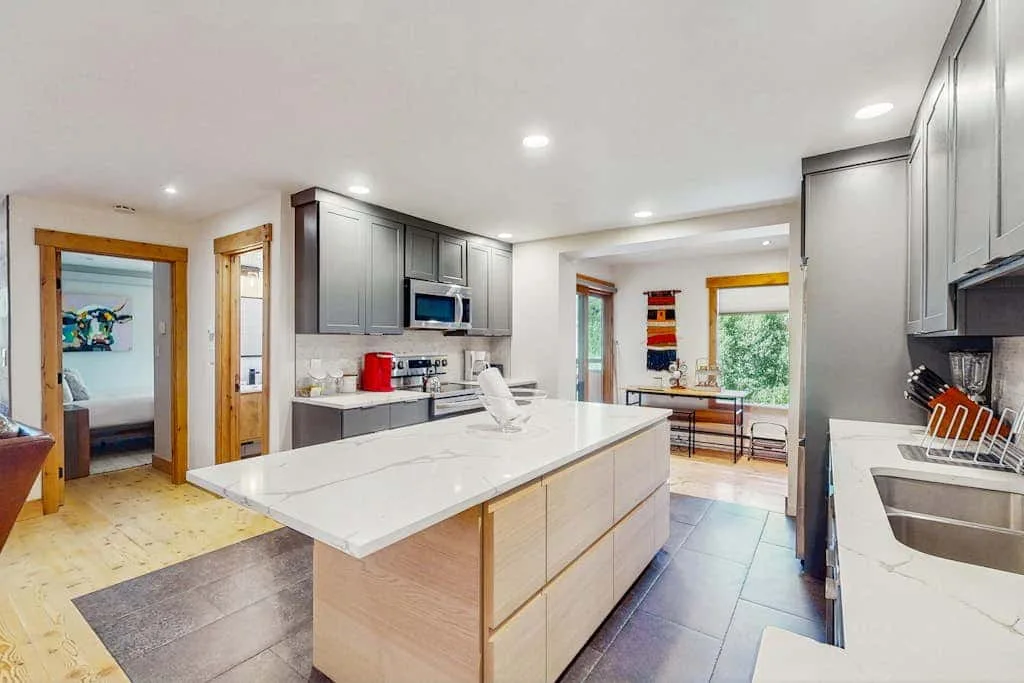 A bright kitchen with a large island and dining area beyond.