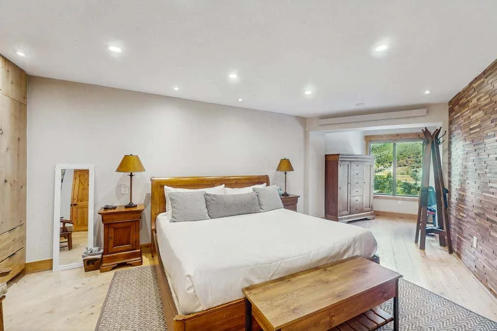 A bedroom with a large bed, wooden bedside tables, and a window.
