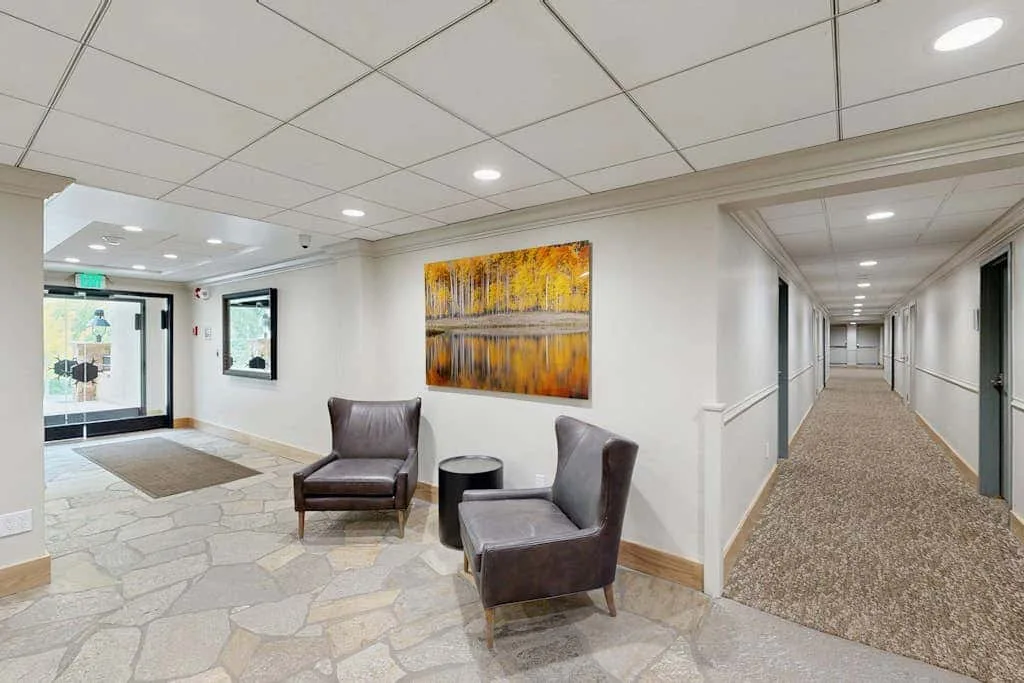 A hallway lobby with seating and a colorful abstract painting.
