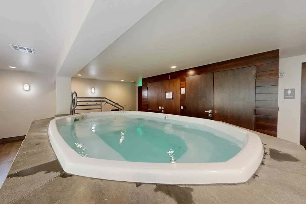 An indoor hot tub sits beside a dark wood-paneled wall.