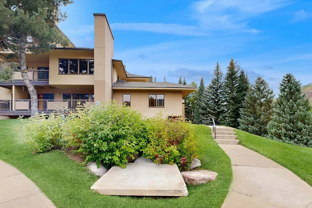 A modern house stands beside a landscaped lawn and curving walkway.