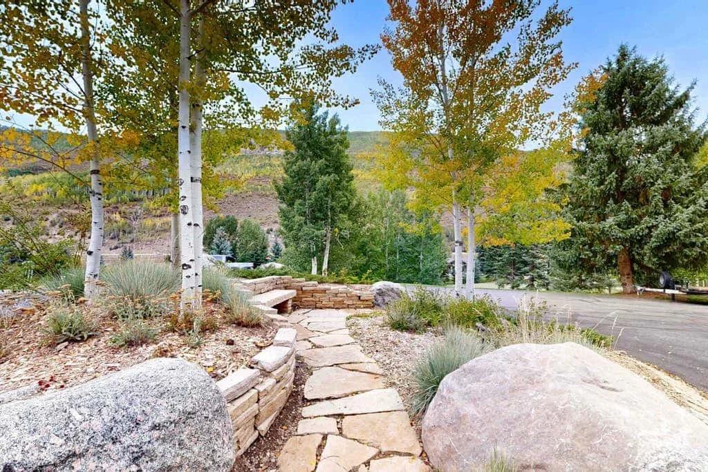 A stone garden path winds between rocks and trees.
