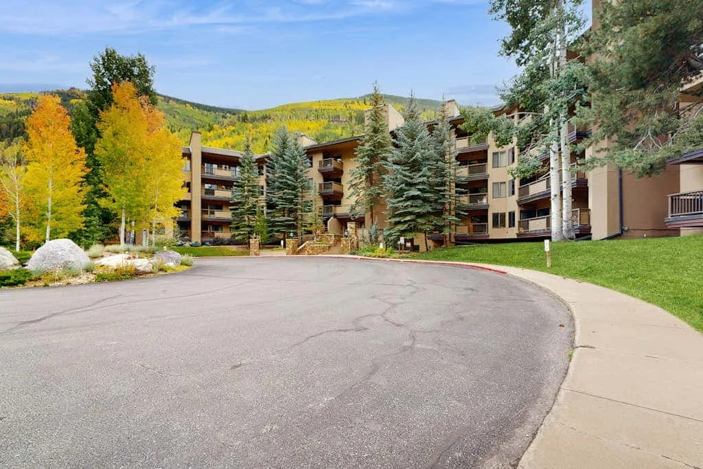 Apartment buildings line a curved driveway beside trees and landscaped grounds.