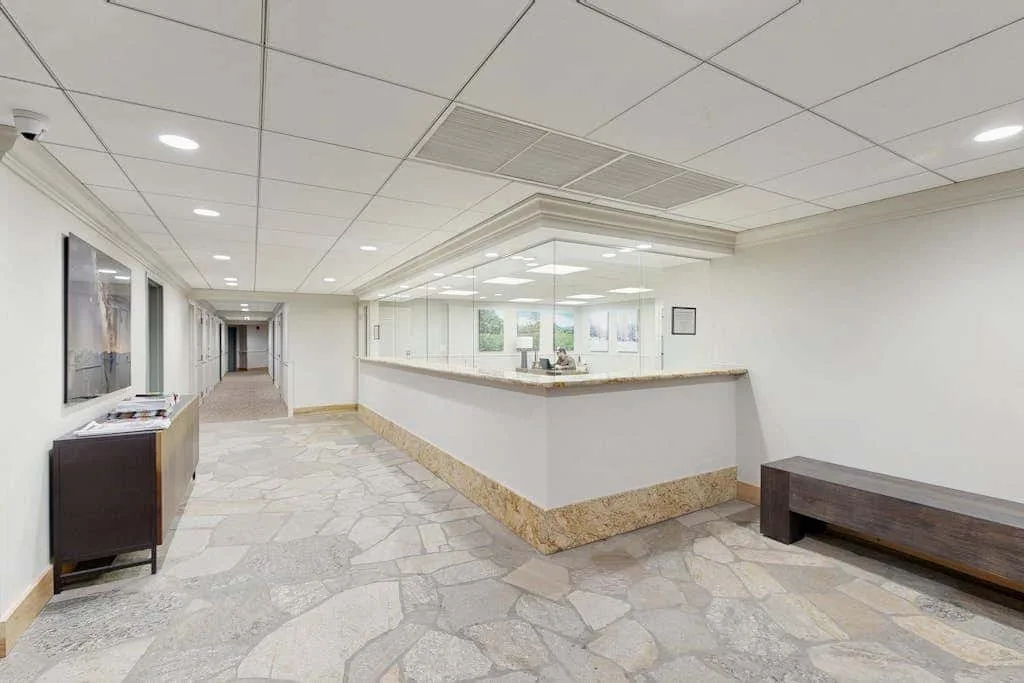 A bright lobby with a reception counter and a long bench.