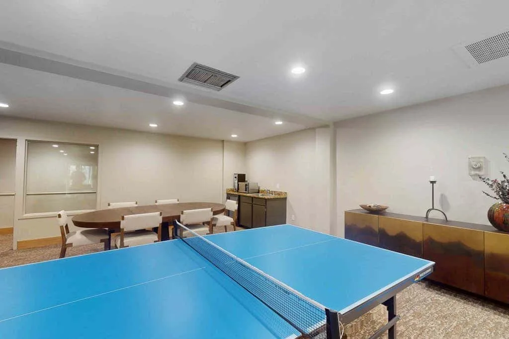 A recreation room with a blue table tennis table and seating along the wall.