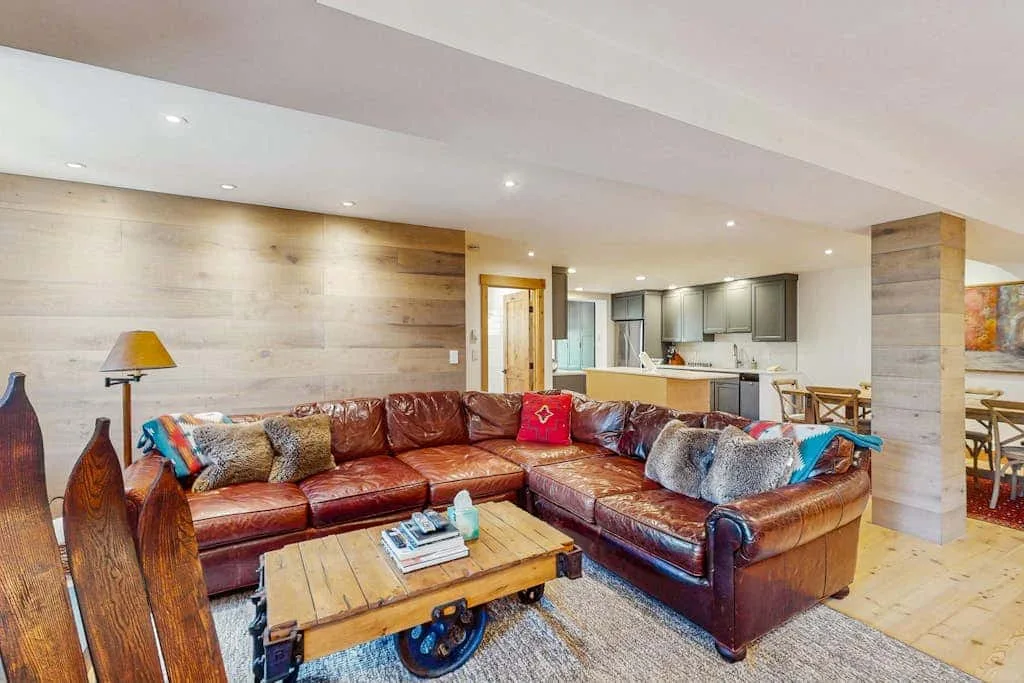 A living room with a leather sectional and an open kitchen.