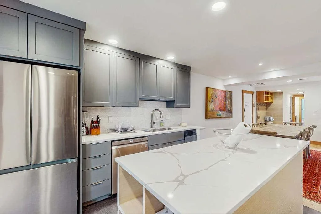 A modern kitchen with gray cabinets and a large white island.