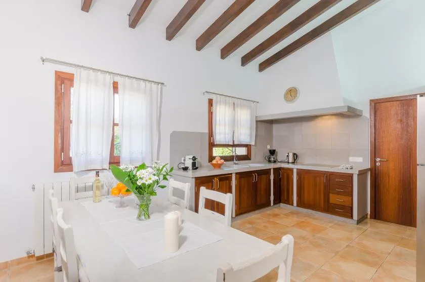 A bright kitchen and dining area with wooden cabinets and a long white table.