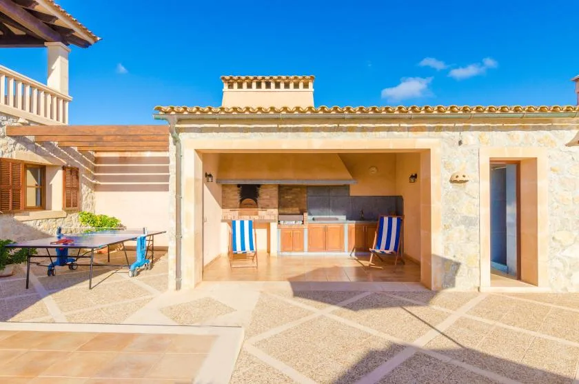A stone patio with a covered outdoor kitchen and seating.