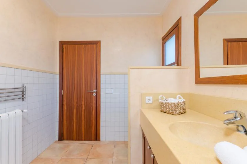 A bathroom with a tiled lower wall and a long vanity with a sink.