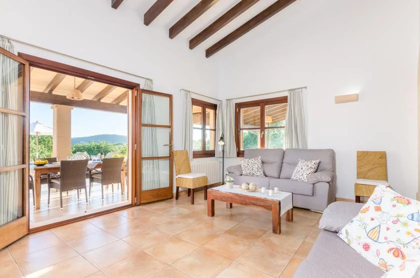 A bright living room with seating, a coffee table, and open doors to a dining area.