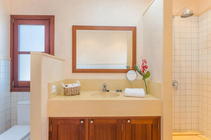 A bathroom vanity with a wide mirror sits beside a tiled shower.