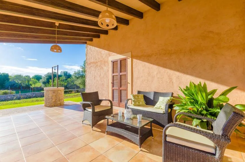 A covered patio seating area with a low table and potted plants.