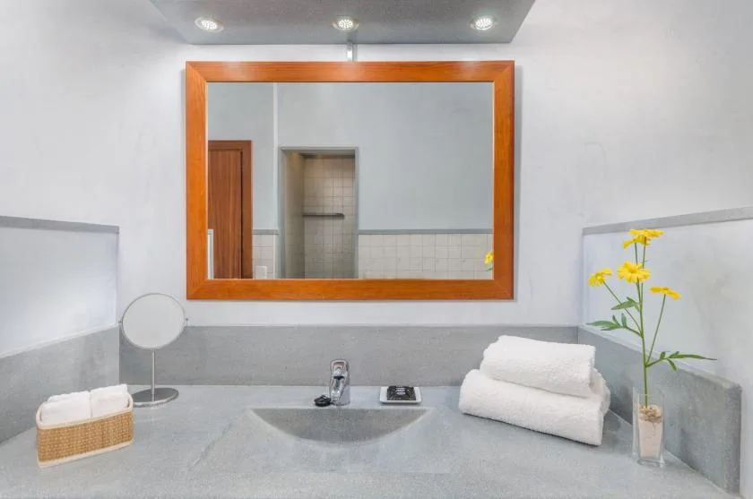 A bathroom vanity with a wide mirror, sink, and folded towels.