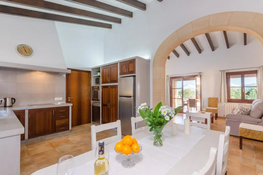An open-plan kitchen and dining area with a table and fresh flowers.