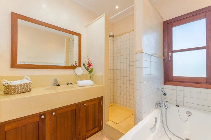 A bathroom vanity and mirror stand beside a shower and bathtub.