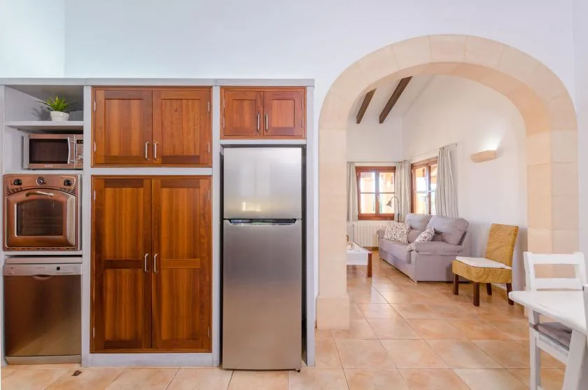 A kitchen opens through an arched doorway into a bright living area with seating.