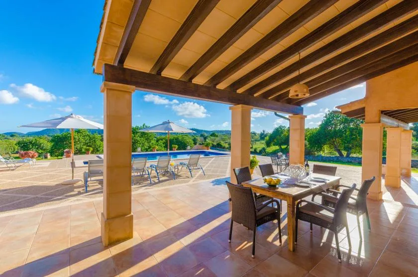 A covered outdoor dining area opens onto a patio with a table and chairs.
