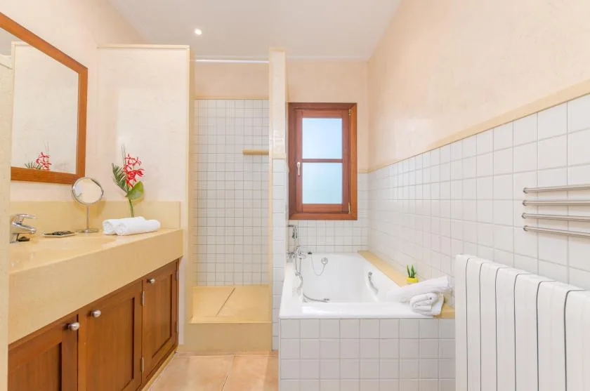 A bright bathroom with a tiled shower area and bathtub.