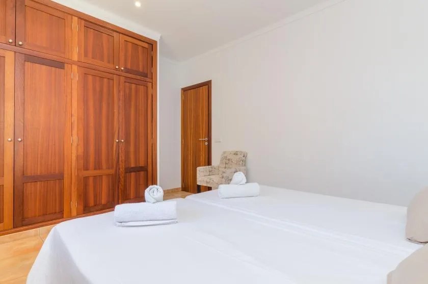 A bedroom with a neatly made bed and built-in wooden wardrobes.