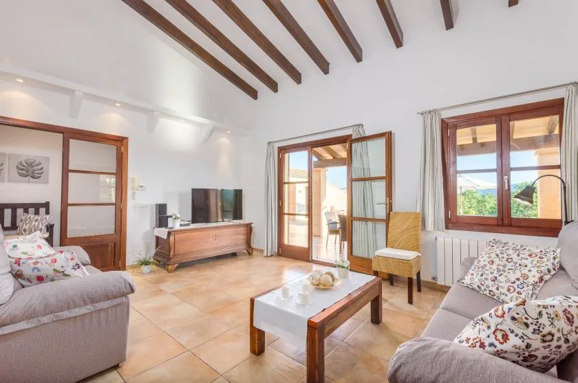 A bright living room with seating, a coffee table, and exposed ceiling beams.