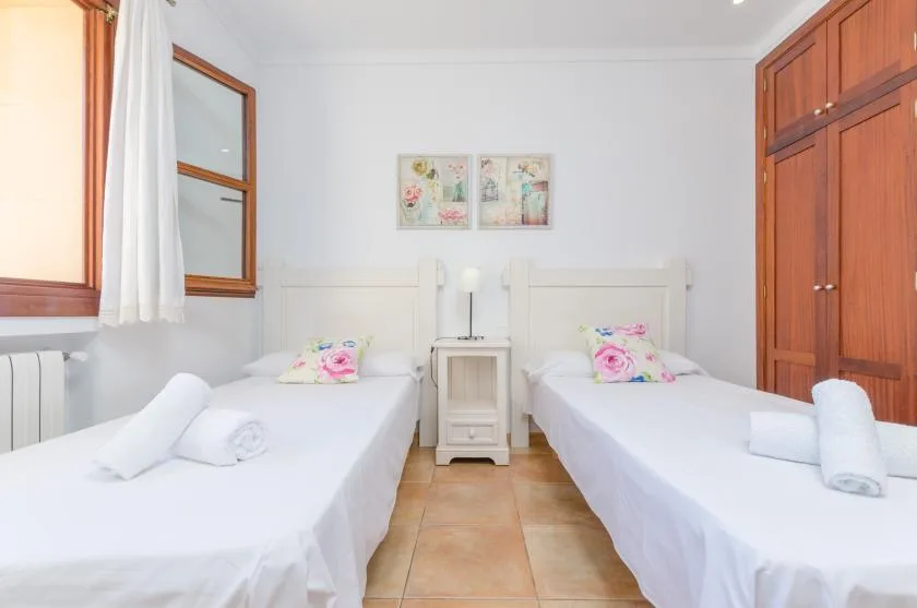A bright bedroom with two single beds and a small bedside table.
