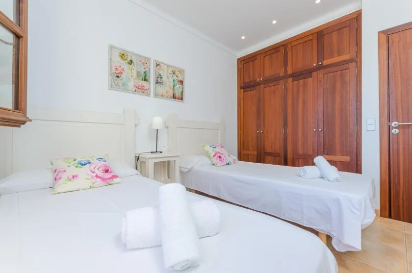 A bedroom with two beds dressed in white linens and colorful pillows.